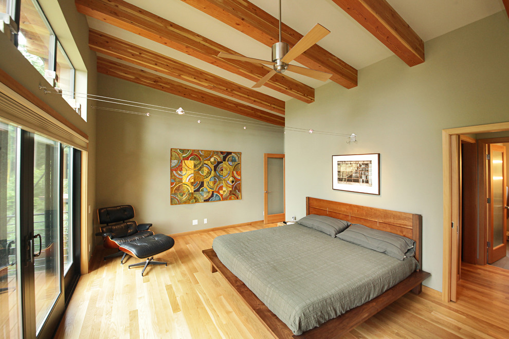 На фото: хозяйская спальня среднего размера в современном стиле с зелеными стенами, светлым паркетным полом и коричневым полом без камина