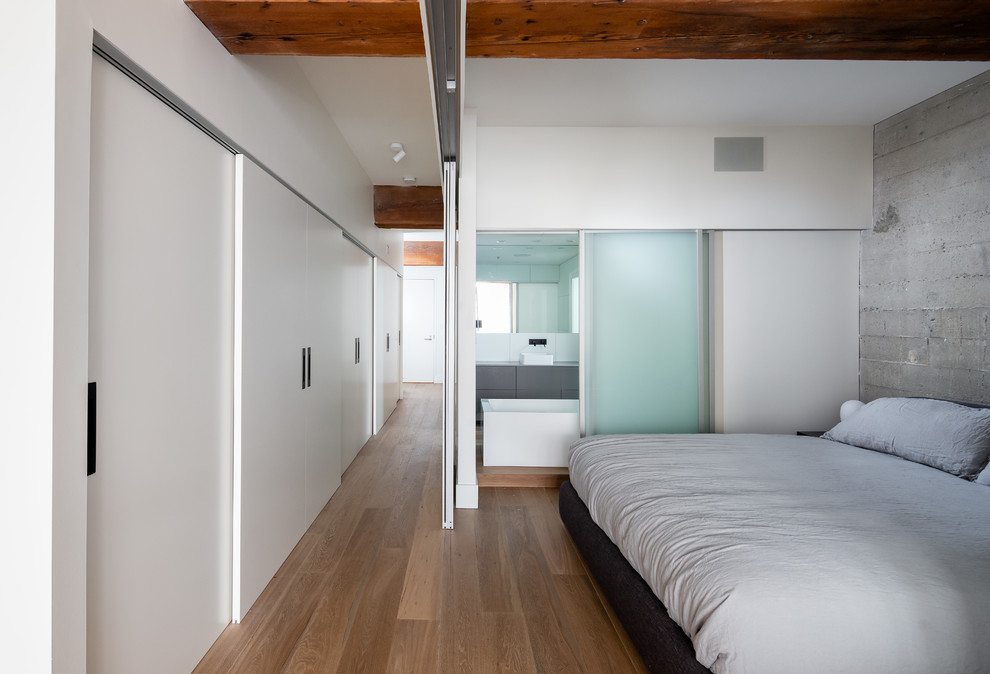 Modelo de dormitorio tipo loft moderno pequeño con paredes grises, suelo de madera clara y suelo marrón