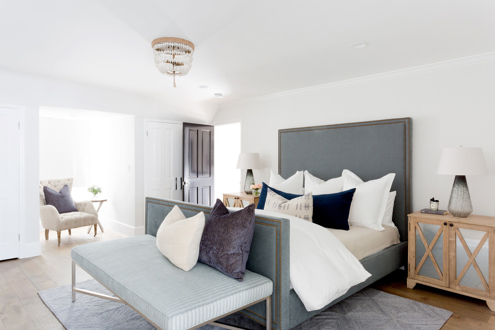 Diseño de dormitorio principal costero con paredes blancas y suelo de madera clara