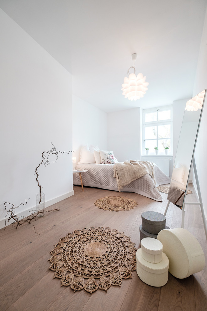 Photo of a scandinavian grey and brown bedroom in Other with white walls, medium hardwood flooring and brown floors.