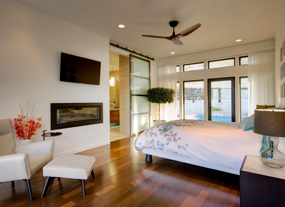На фото: спальня в современном стиле с горизонтальным камином и тюлем