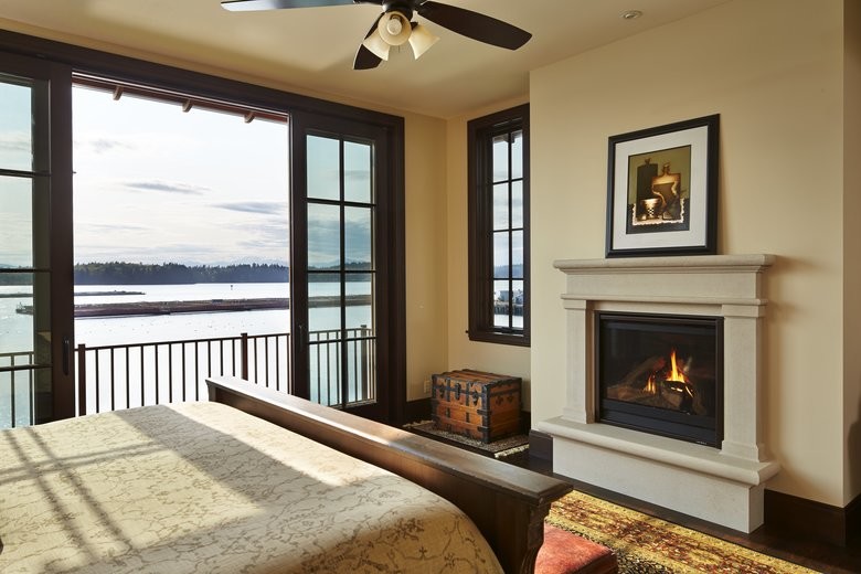 Large traditional bedroom in Seattle with beige walls, dark hardwood flooring, a standard fireplace and a stone fireplace surround.
