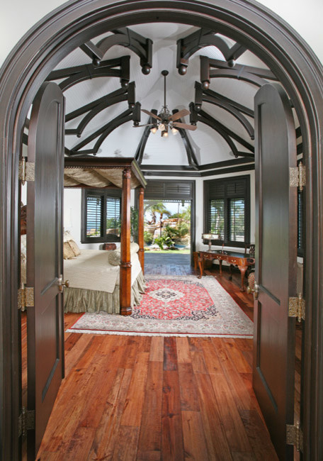 Ispirazione per una grande camera matrimoniale tropicale con pareti bianche e pavimento in legno massello medio