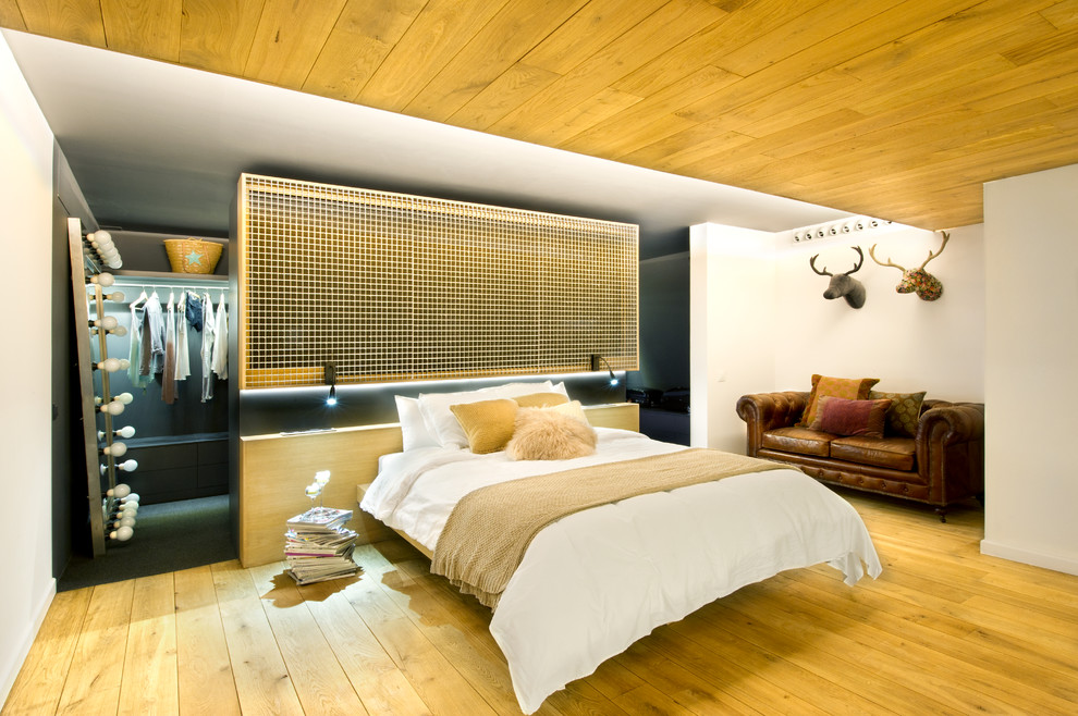 Imagen de dormitorio tipo loft urbano con paredes blancas y suelo de madera en tonos medios