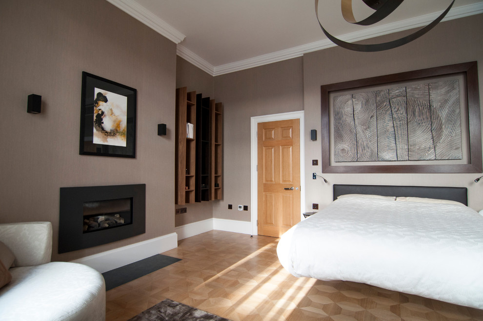 Inspiration pour une chambre parentale design de taille moyenne avec un mur marron, un sol en bois brun, une cheminée standard et un manteau de cheminée en métal.