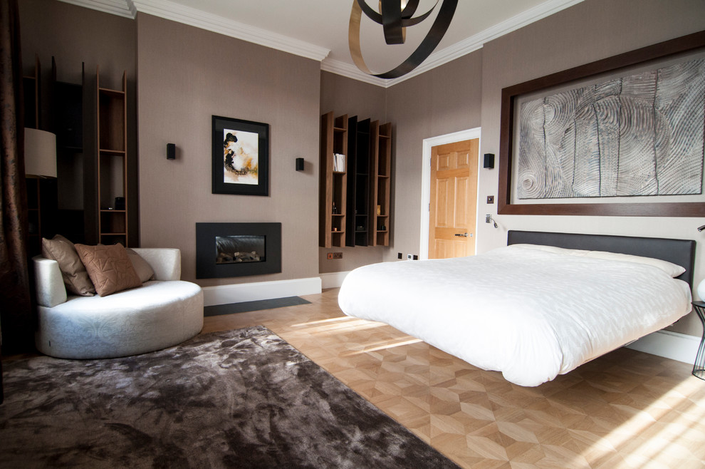 Ejemplo de dormitorio principal actual de tamaño medio con suelo de madera en tonos medios, todas las chimeneas, marco de chimenea de metal y paredes grises