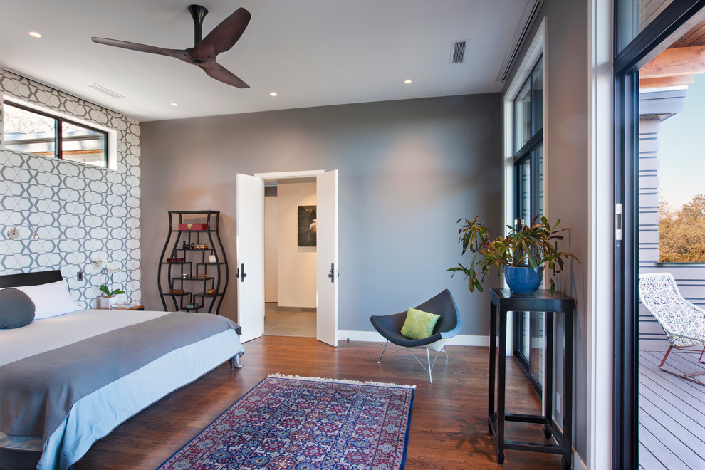 オースティンにある広いコンテンポラリースタイルのおしゃれな客用寝室 (グレーの壁、無垢フローリング、暖炉なし、アクセントウォール)