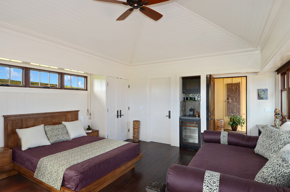 Imagen de habitación de invitados tropical de tamaño medio sin chimenea con paredes blancas y suelo de madera oscura