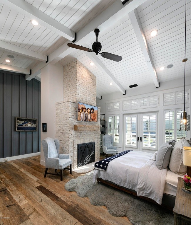 Foto de dormitorio principal campestre grande con paredes blancas, suelo de madera en tonos medios, todas las chimeneas, marco de chimenea de ladrillo y suelo marrón