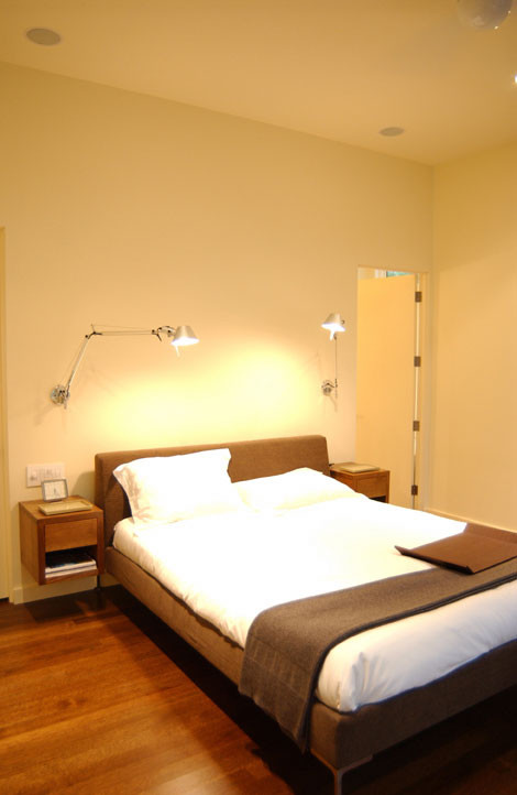 Ejemplo de dormitorio minimalista con suelo de madera en tonos medios