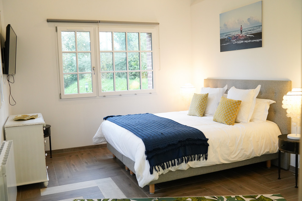 Immagine di una piccola camera degli ospiti stile marinaro con pareti bianche, pavimento in gres porcellanato e pavimento marrone