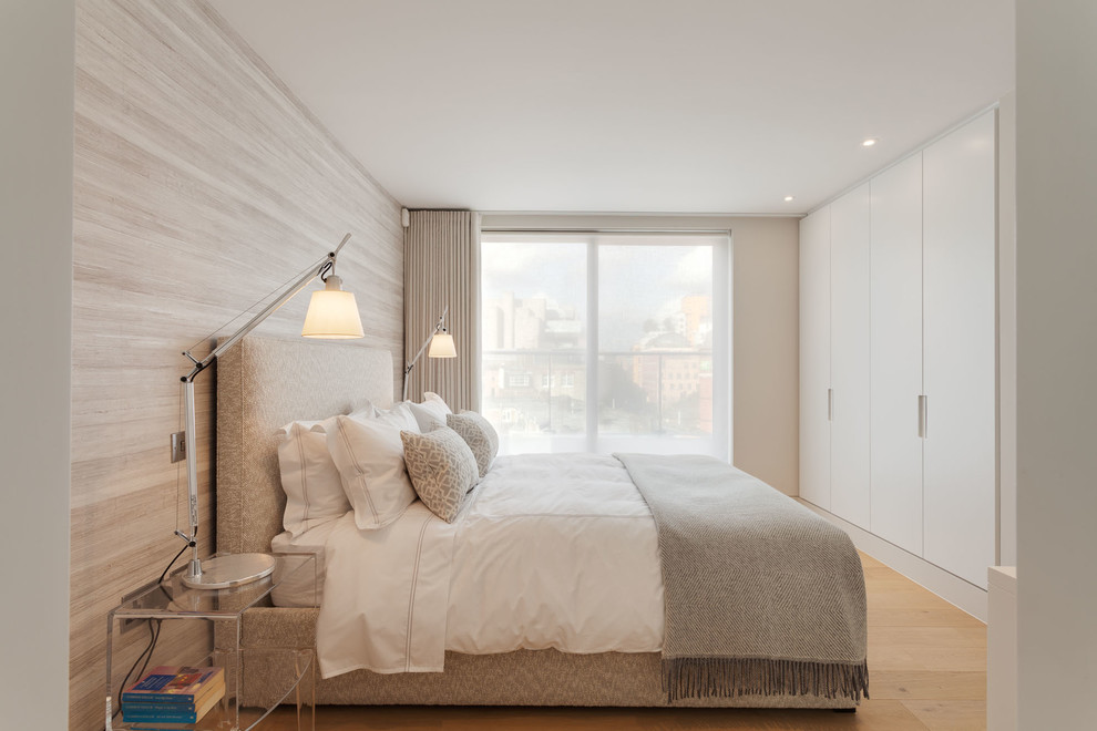 Photo of a medium sized contemporary guest bedroom in London with beige walls, light hardwood flooring, no fireplace and a feature wall.