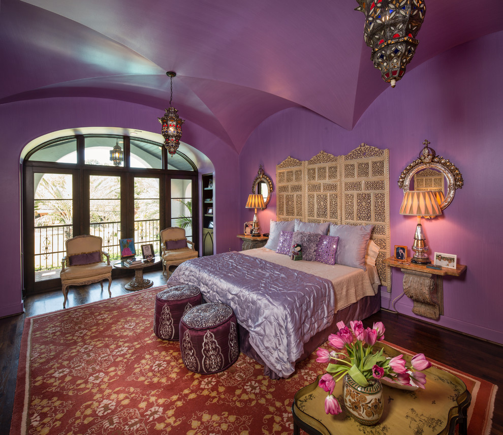 Großes Mediterranes Hauptschlafzimmer mit lila Wandfarbe und dunklem Holzboden in Houston