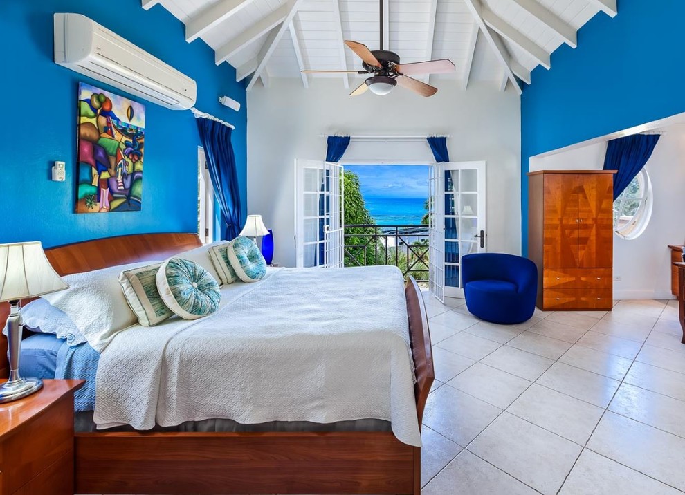 Imagen de dormitorio tropical extra grande con paredes multicolor y suelo beige