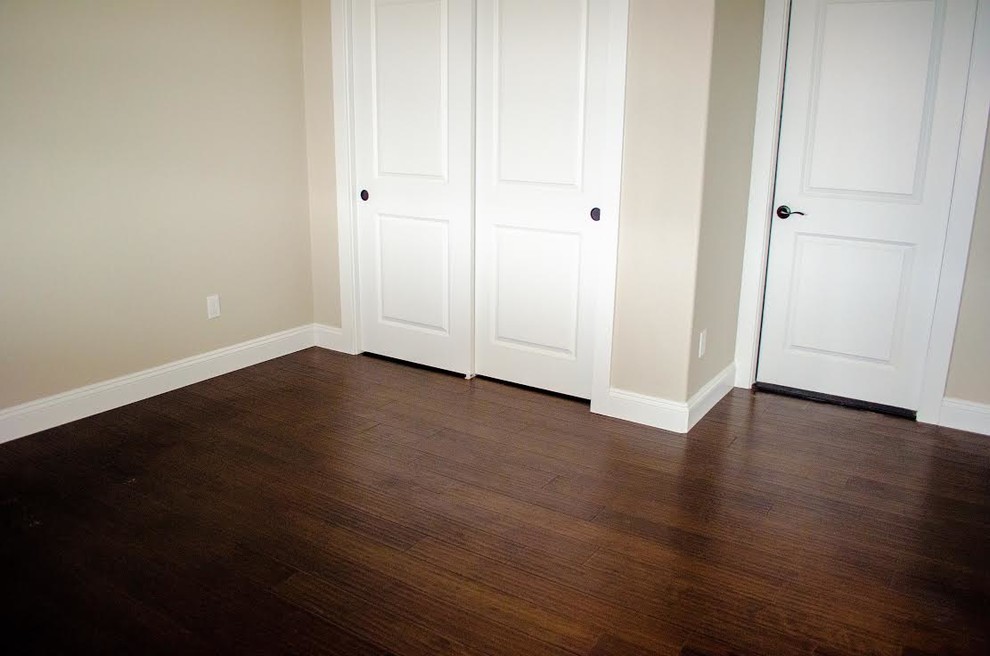 Modelo de habitación de invitados clásica pequeña sin chimenea con paredes beige, suelo de madera oscura y suelo marrón