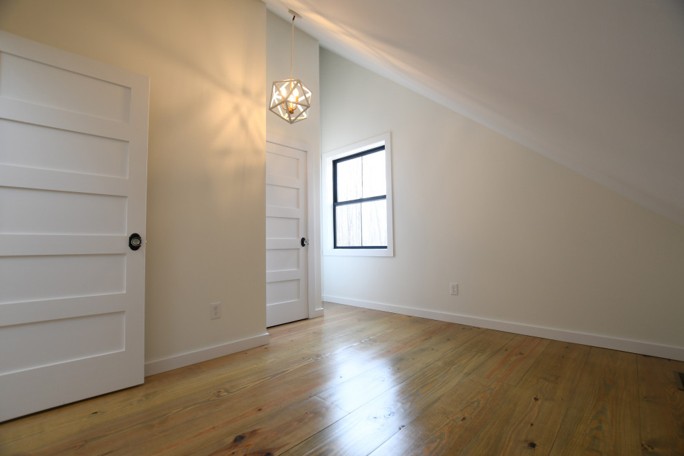 Immagine di una camera degli ospiti country di medie dimensioni con pareti bianche, pavimento in legno massello medio, nessun camino e pavimento marrone