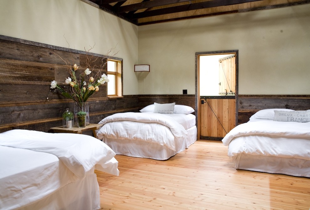 Example of a large country guest light wood floor and orange floor bedroom design in Seattle with beige walls and no fireplace