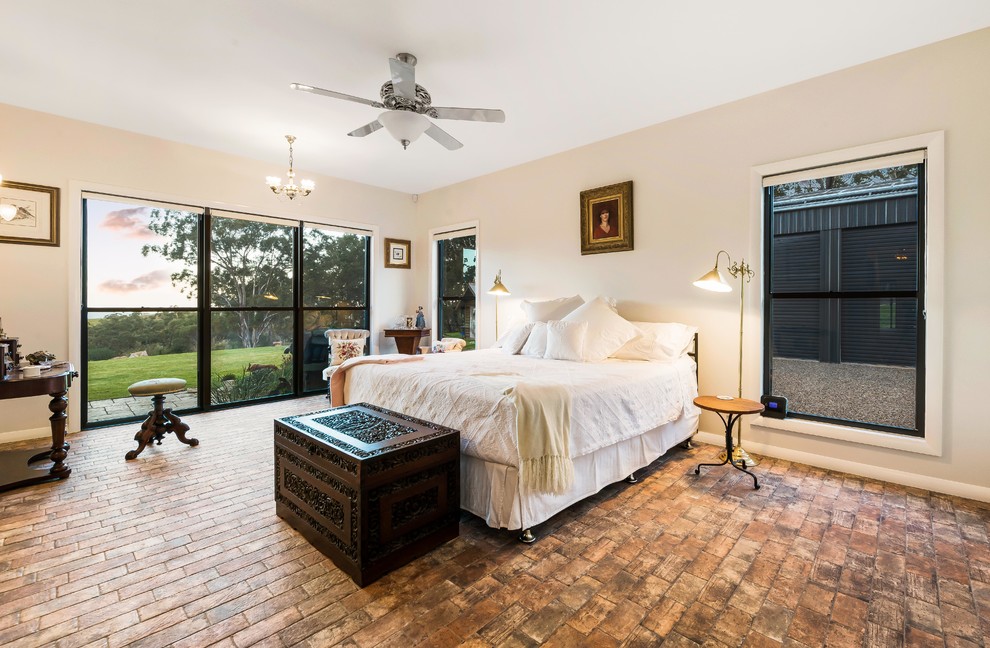 Diseño de dormitorio principal de estilo de casa de campo con paredes beige, suelo de ladrillo y suelo marrón