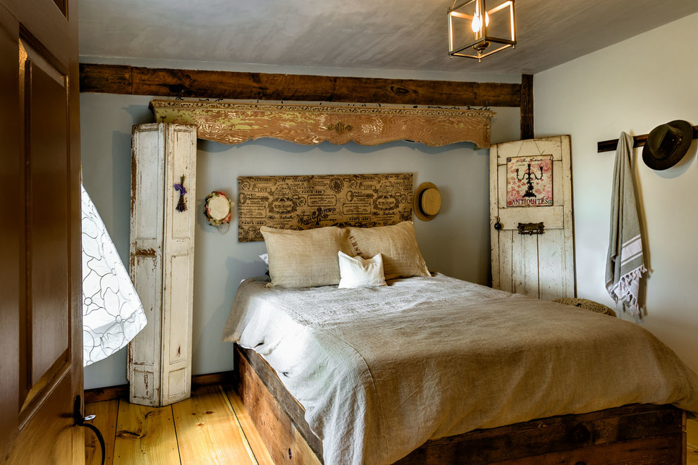 Immagine di una camera da letto country con pareti grigie, pavimento in legno massello medio e nessun camino