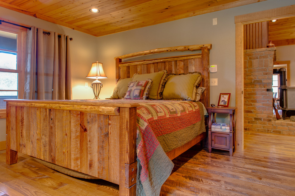 Imagen de dormitorio principal rústico de tamaño medio sin chimenea con paredes beige y suelo de madera clara