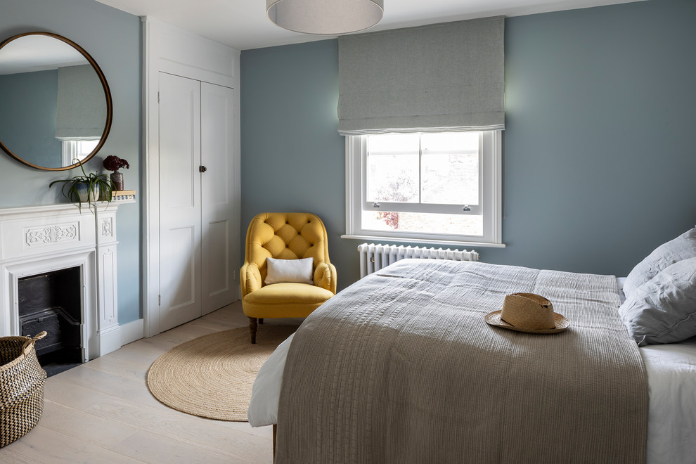 Пример оригинального дизайна: гостевая спальня (комната для гостей), среднего размера в стиле неоклассика (современная классика) с синими стенами, светлым паркетным полом, стандартным камином, фасадом камина из штукатурки и бежевым полом
