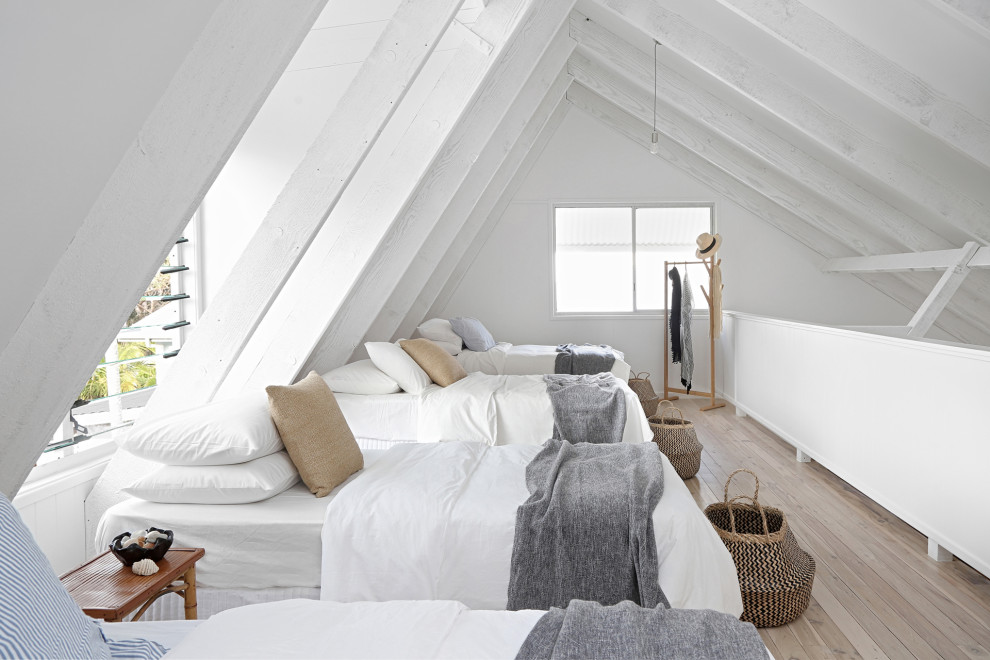 Ejemplo de dormitorio tipo loft y abovedado costero con paredes blancas, suelo de madera clara, suelo beige y vigas vistas