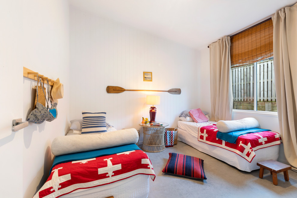 Ejemplo de habitación de invitados abovedada costera de tamaño medio con paredes blancas, suelo gris, machihembrado y suelo de cemento