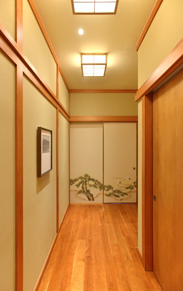 Aménagement d'une chambre d'amis asiatique de taille moyenne avec un mur jaune, un sol en bois brun et un sol marron.