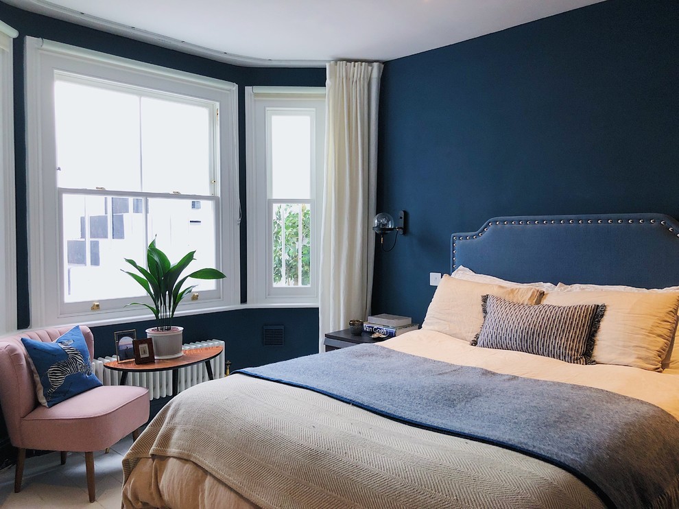 Klassisches Gästezimmer mit blauer Wandfarbe, gebeiztem Holzboden und weißem Boden in London