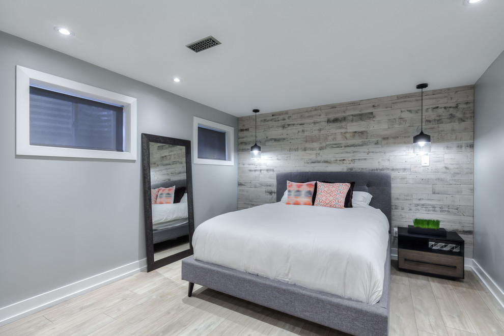 Foto di una camera da letto stile loft contemporanea di medie dimensioni con pareti grigie, pavimento in laminato e pavimento marrone