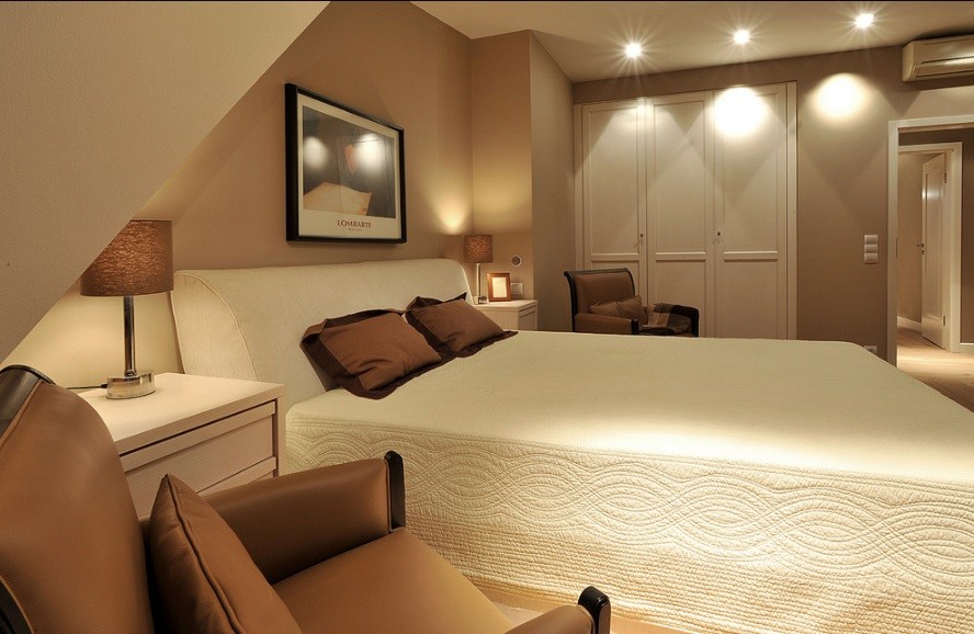 Foto de dormitorio principal moderno pequeño con paredes beige, suelo de madera clara y suelo marrón