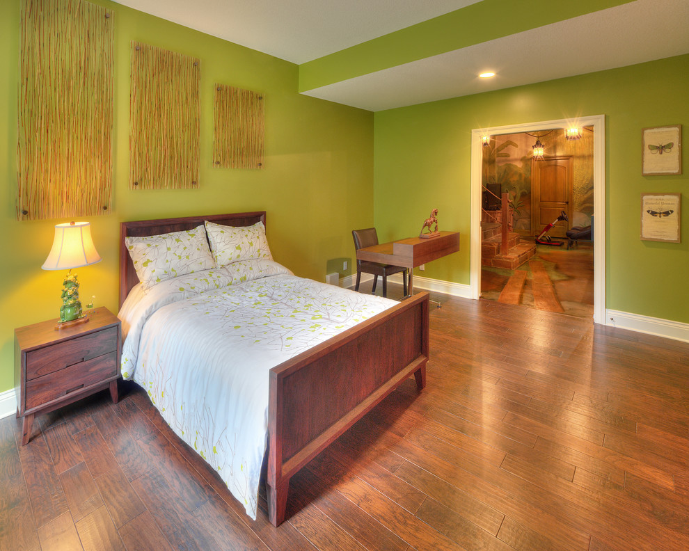 Idée de décoration pour une grande chambre design avec un mur vert et un sol en bois brun.