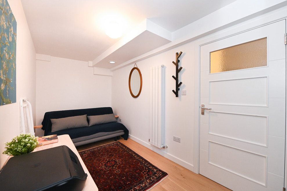 Cette image montre une chambre parentale chalet de taille moyenne avec un mur blanc, parquet clair, aucune cheminée, un manteau de cheminée en plâtre et un sol marron.