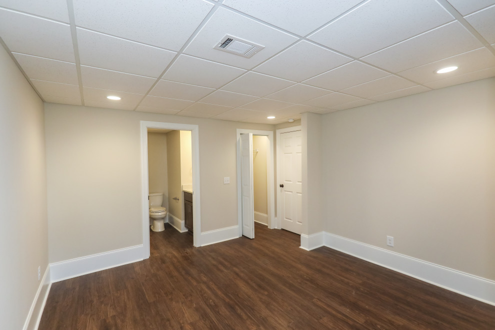 Imagen de habitación de invitados clásica renovada de tamaño medio con paredes beige, suelo vinílico y suelo marrón