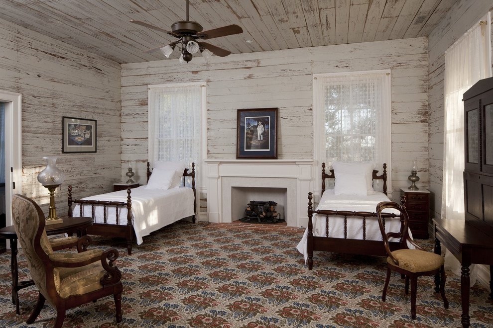Example of a country guest bedroom design in Austin with a standard fireplace and white walls