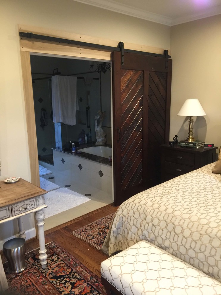 Ejemplo de dormitorio principal rústico de tamaño medio sin chimenea con paredes beige y suelo de madera en tonos medios