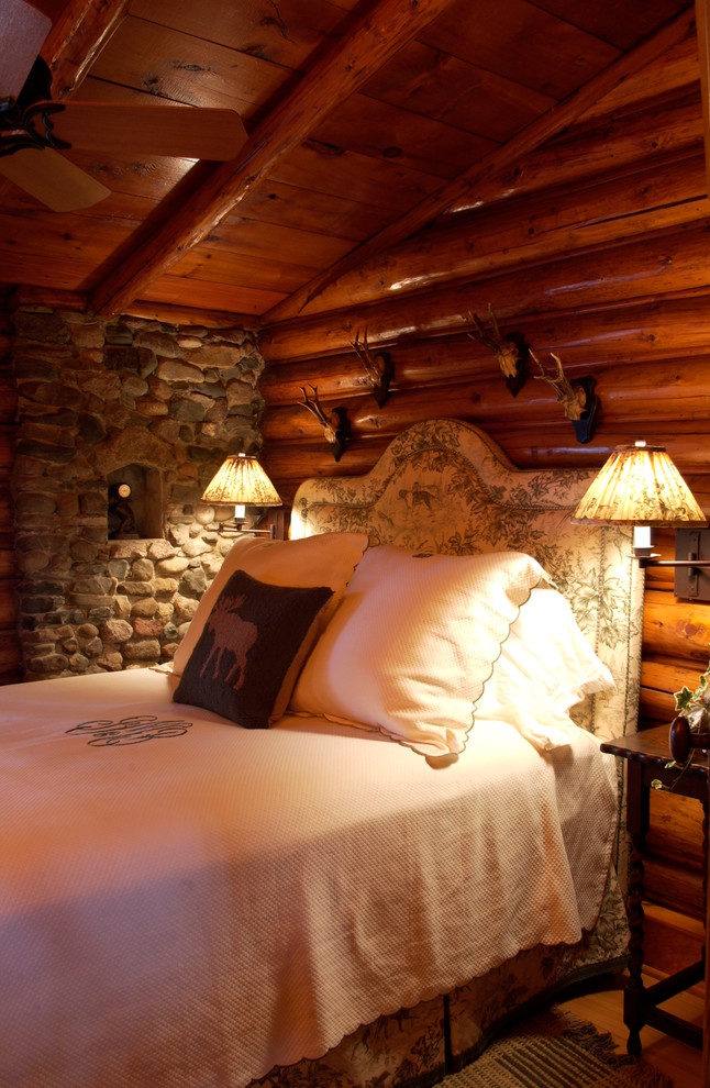 Idée de décoration pour une chambre d'amis chalet de taille moyenne avec un mur marron et un sol en bois brun.