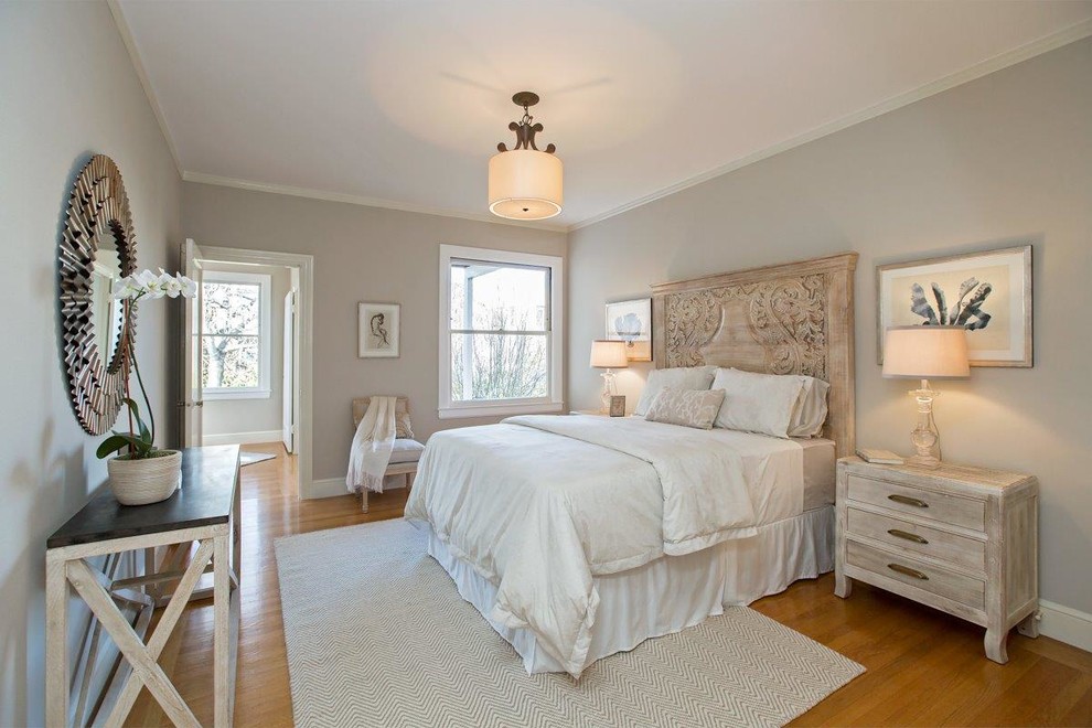 Modelo de dormitorio principal clásico de tamaño medio sin chimenea con paredes grises, suelo de madera clara y suelo marrón