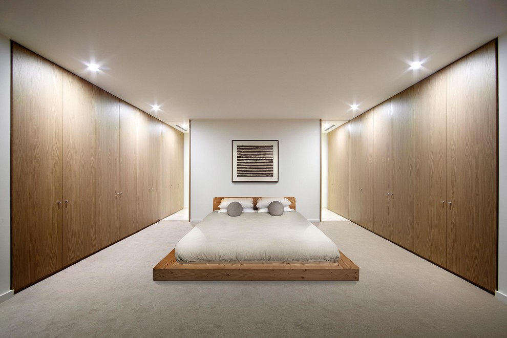 Modelo de dormitorio nórdico con moqueta y paredes blancas