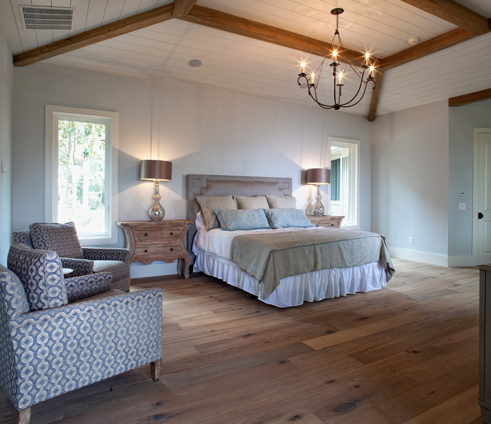 Large world-inspired master bedroom in Charleston with medium hardwood flooring, white walls and brown floors.