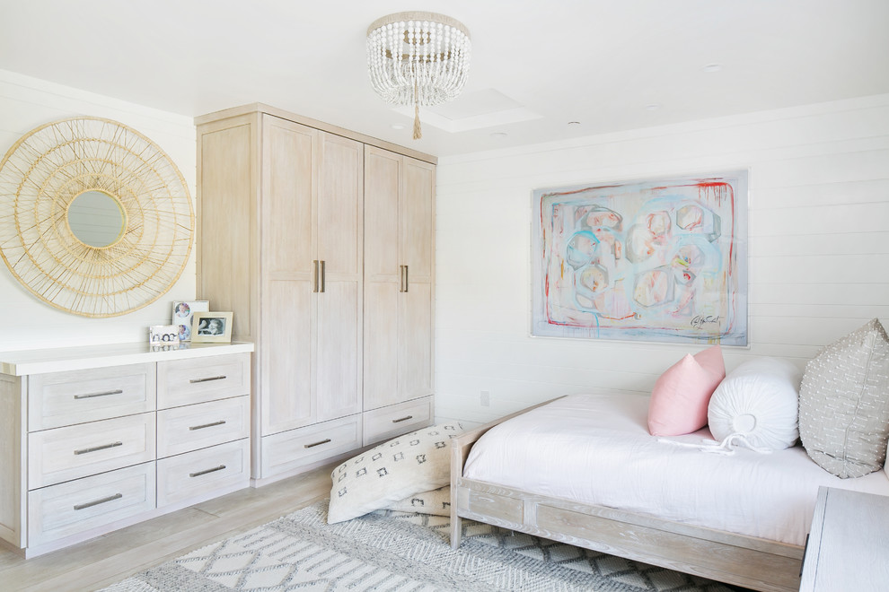 This is an example of a beach style bedroom in Orange County with white walls and light hardwood flooring.