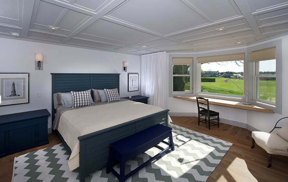 Ejemplo de dormitorio principal costero grande sin chimenea con paredes blancas y suelo de madera en tonos medios