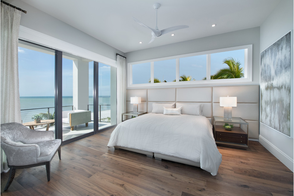 Example of a large trendy master medium tone wood floor and brown floor bedroom design in Miami with gray walls and no fireplace