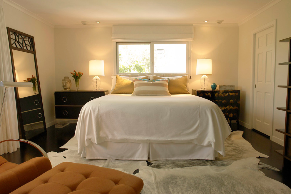 Modelo de dormitorio principal costero de tamaño medio con paredes blancas, suelo de madera oscura, marco de chimenea de baldosas y/o azulejos, chimenea de esquina y suelo marrón