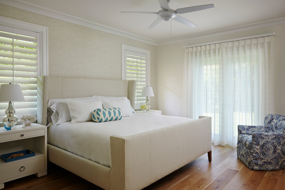 Diseño de dormitorio costero de tamaño medio sin chimenea con paredes beige y suelo de madera en tonos medios