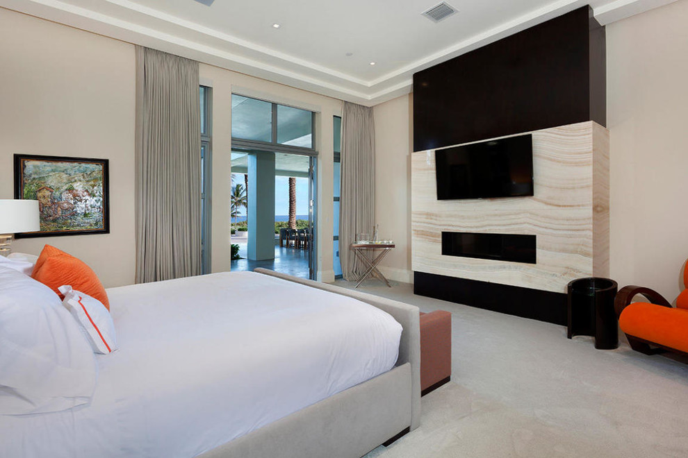 マイアミにある巨大なコンテンポラリースタイルのおしゃれな客用寝室 (ベージュの壁、カーペット敷き、横長型暖炉、石材の暖炉まわり)