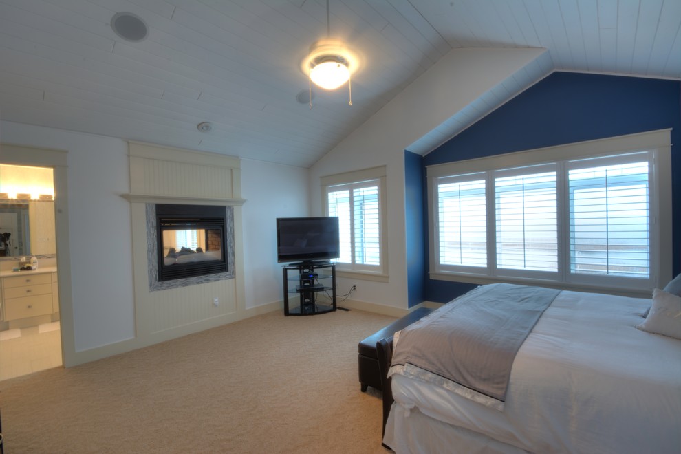 Imagen de dormitorio principal clásico de tamaño medio con paredes blancas, moqueta, chimenea de doble cara, marco de chimenea de madera y suelo beige