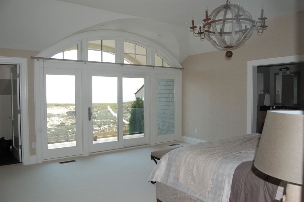 Large beach style master bedroom in Boston with beige walls and carpet.