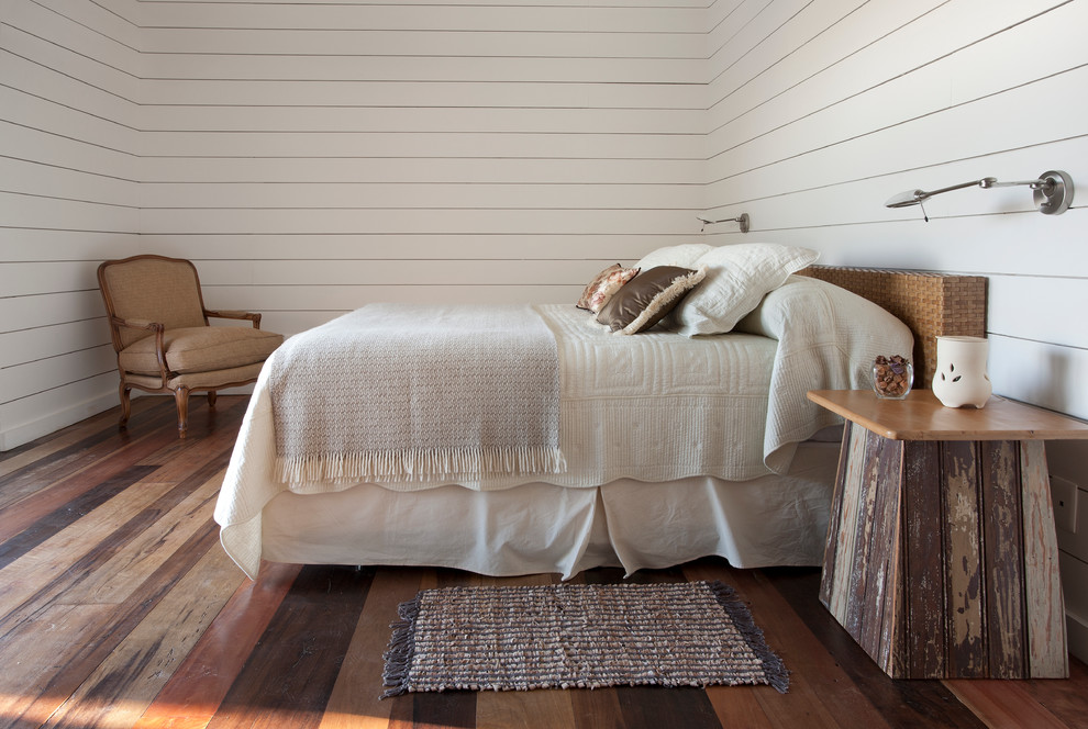Aménagement d'une chambre d'amis blanche et bois bord de mer avec un mur blanc, un sol en bois brun et aucune cheminée.