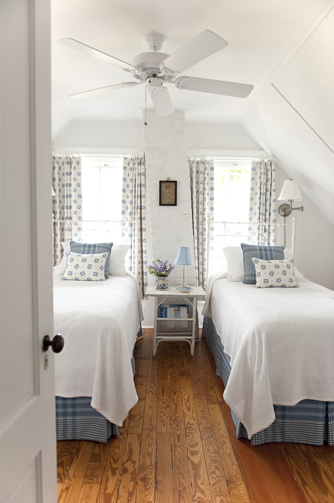 Example of a mid-sized beach style guest medium tone wood floor bedroom design in New York with white walls and no fireplace